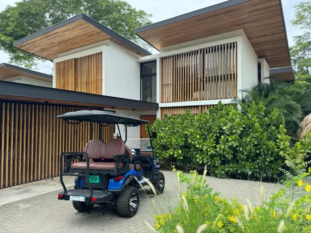 Golf cart parked at a luxury wood and stone villa in Playa Grande